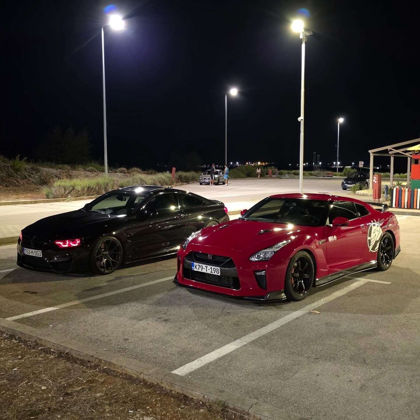 Crveni GT-R i crni BMW noću na parkingu