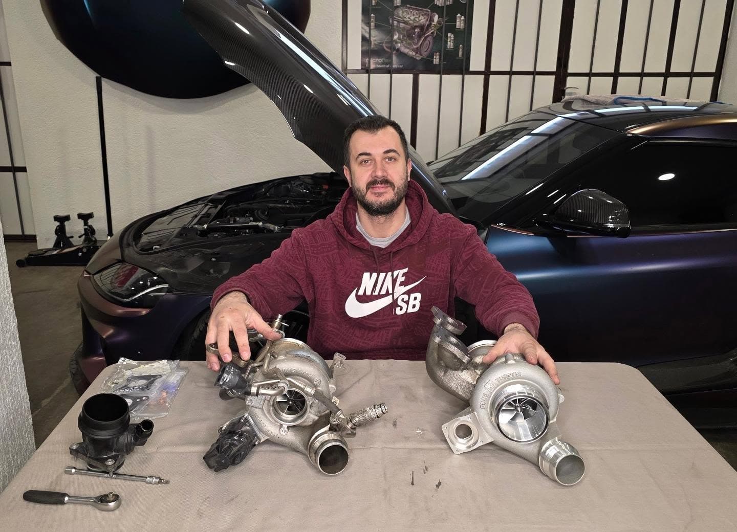 Serijska i nadograđena turbina na stolu ispred auta otvorene haube