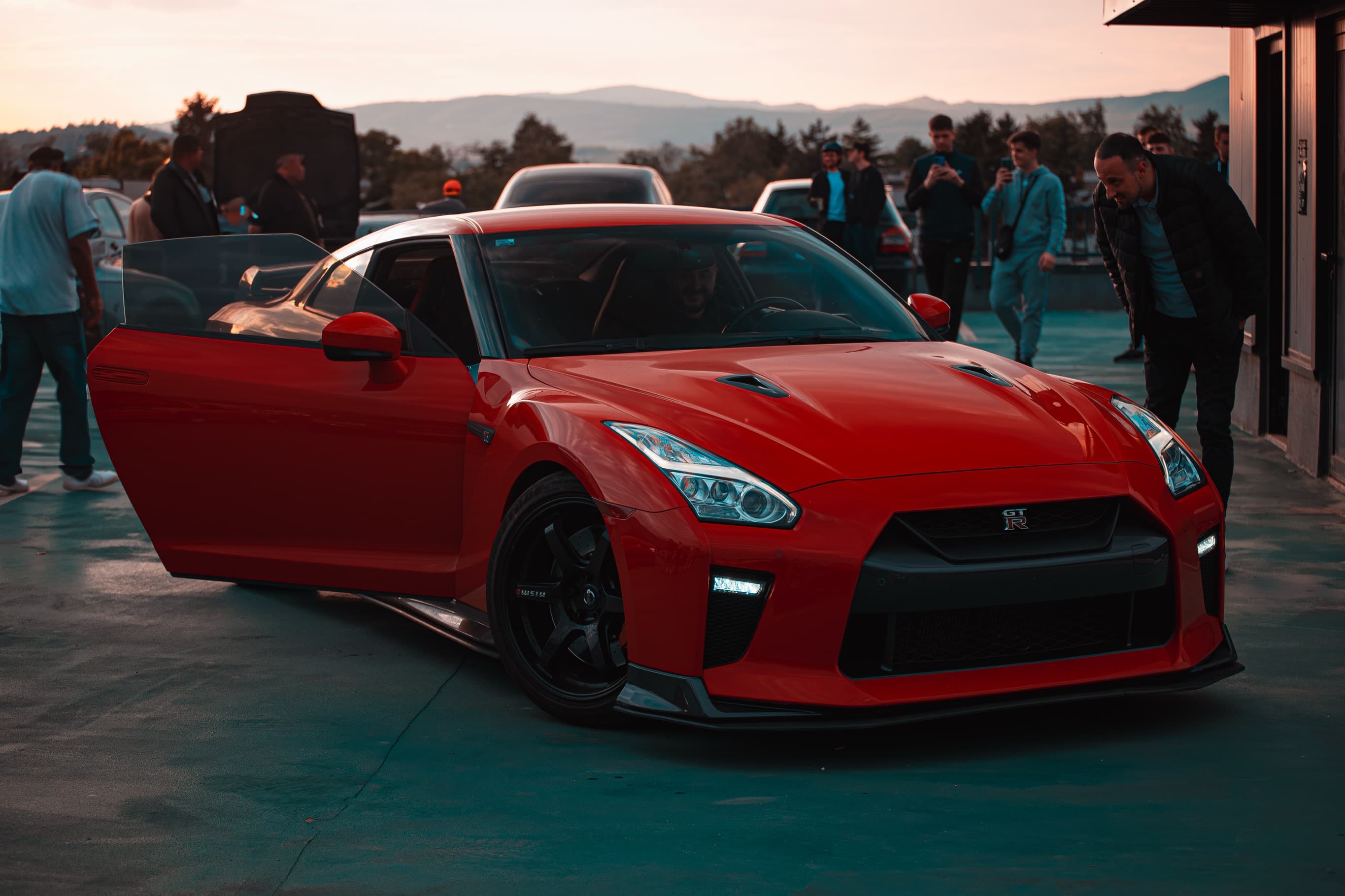 Crveni Nissan GT-R R35 otvorenih vrata na okupljanju, zalazak sunca